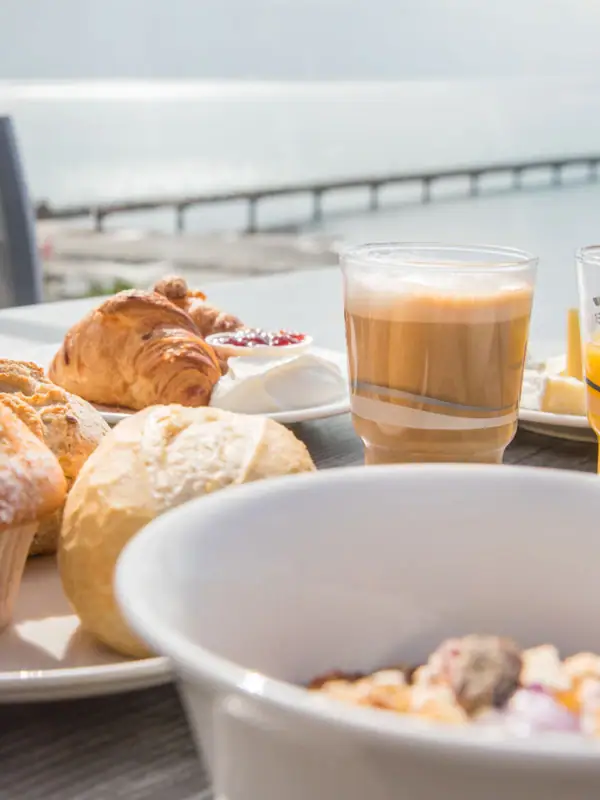 A table with various food and drinks, including pastries and cups.