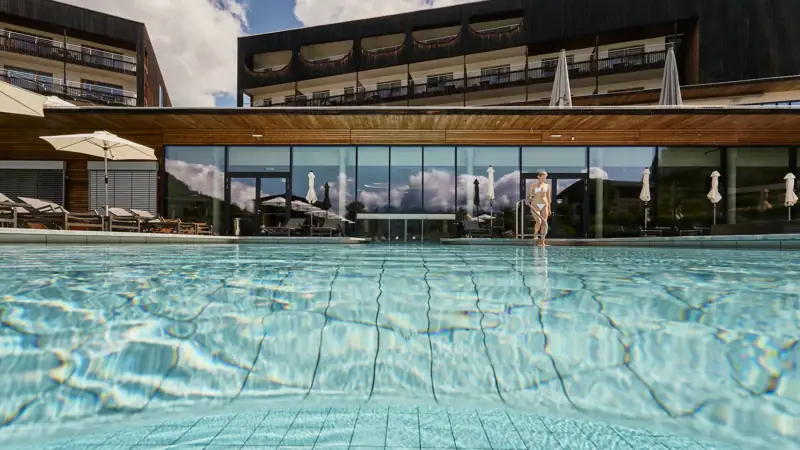 Swimming pool with the aja Bergresort Werfenweng in the background.