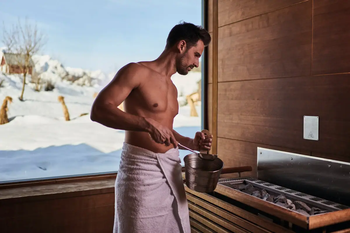 A man in a towel is cooking in a sauna.