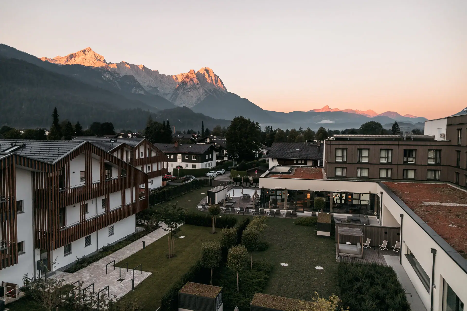 A group of buildings with trees and mountains in the background.
