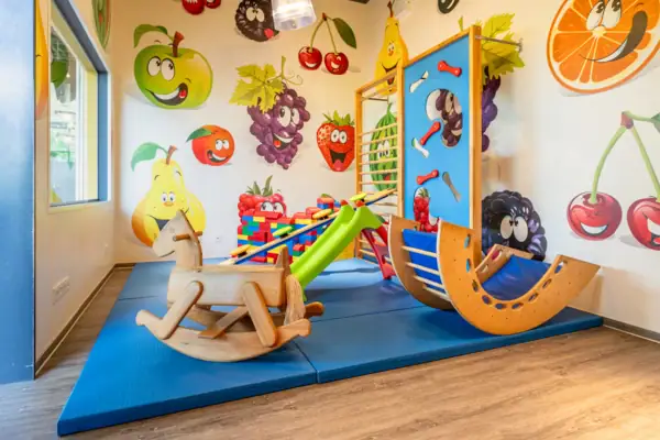 Play area in a room with children's art on the wall.