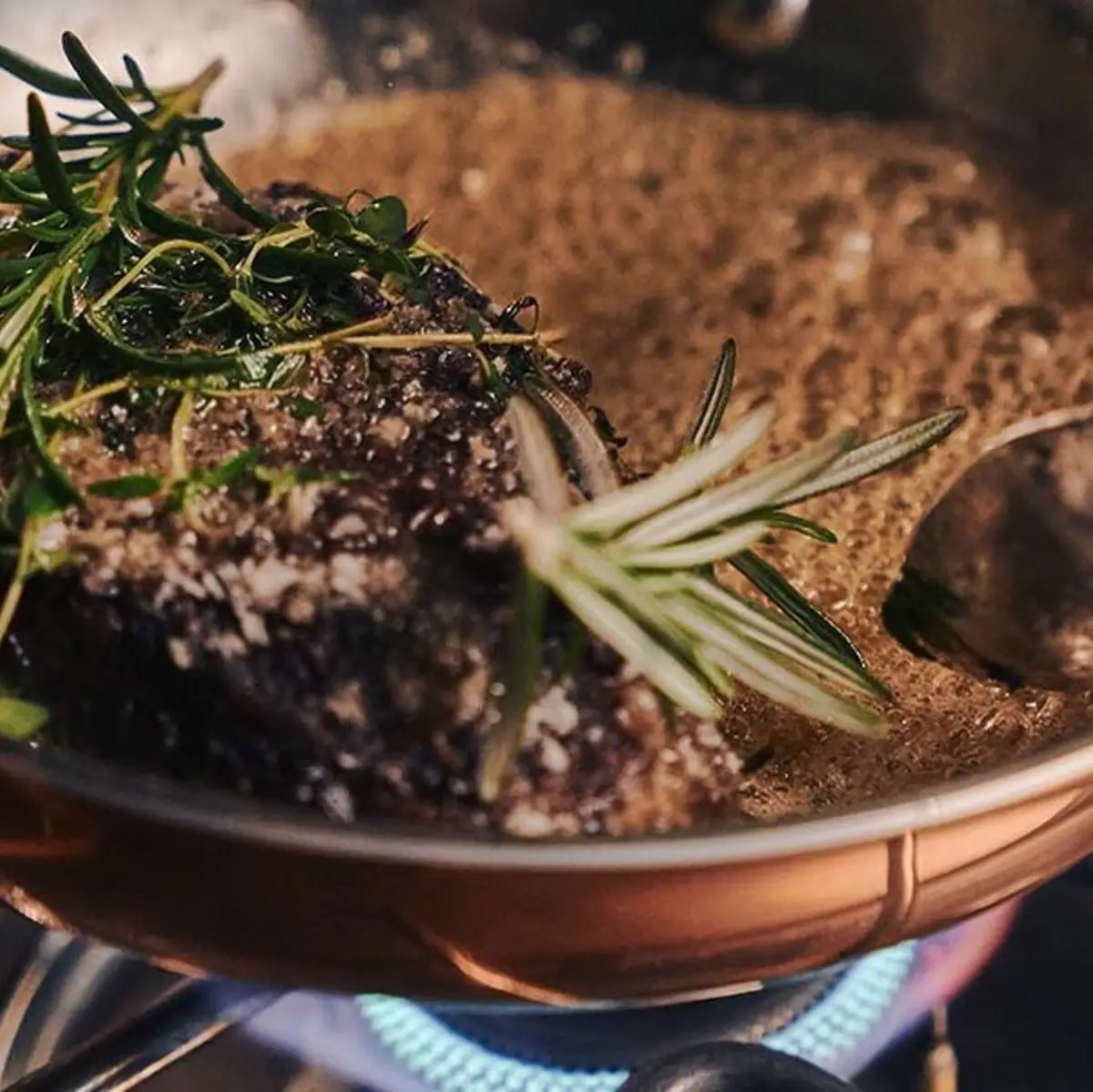A pot with a piece of meat and a spoon.
