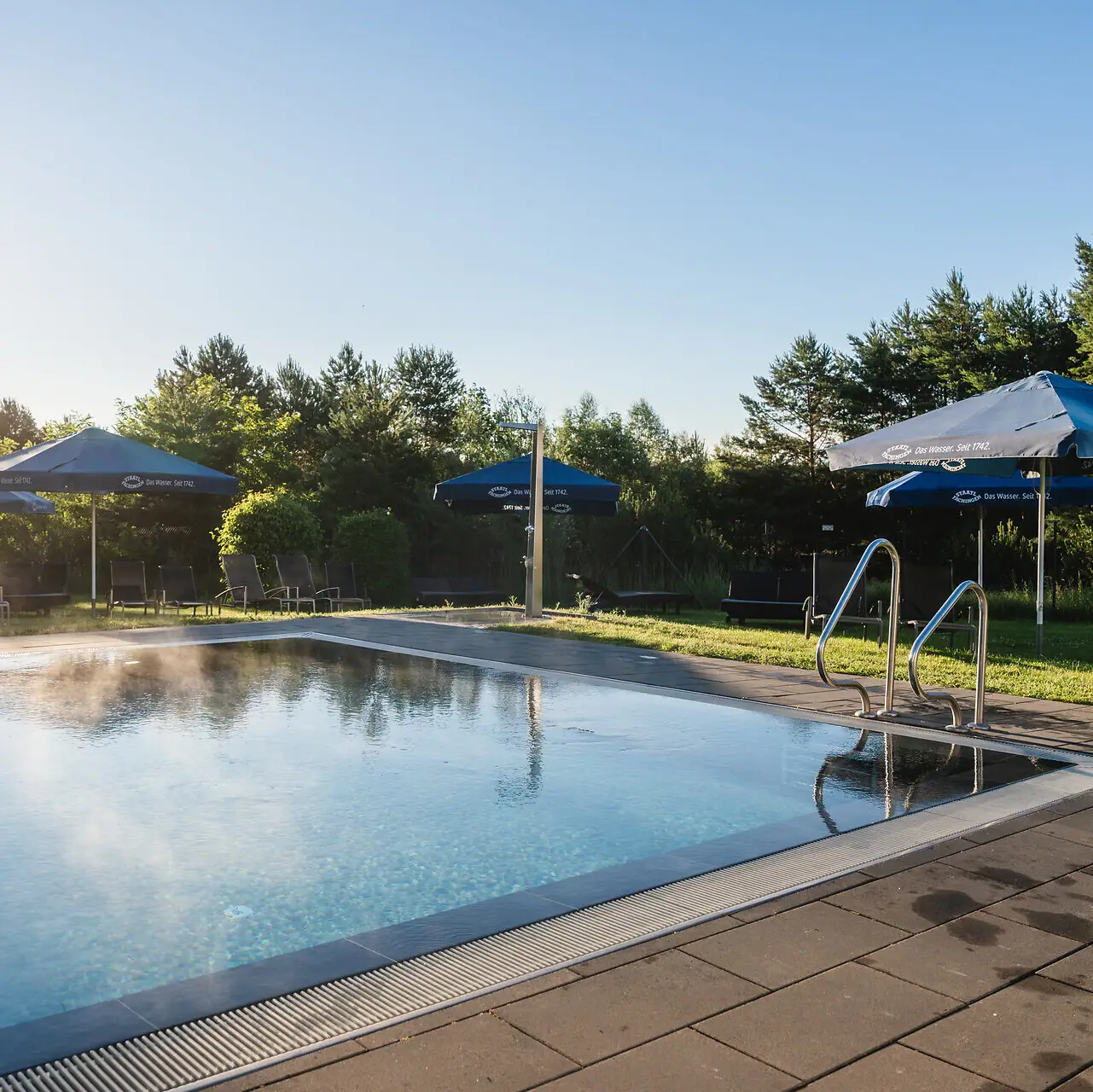 Outdoor pool aja Bad Saarow An outdoor pool with parasols and surrounding grass.