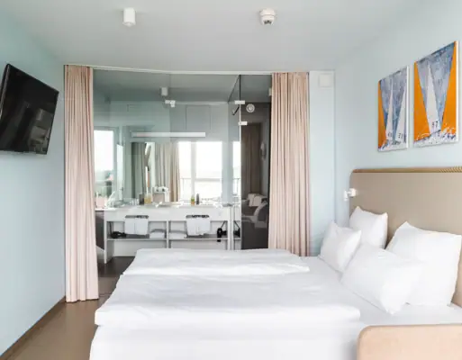 Rooms at the aja Travemünde A room with a bed and a mirror.