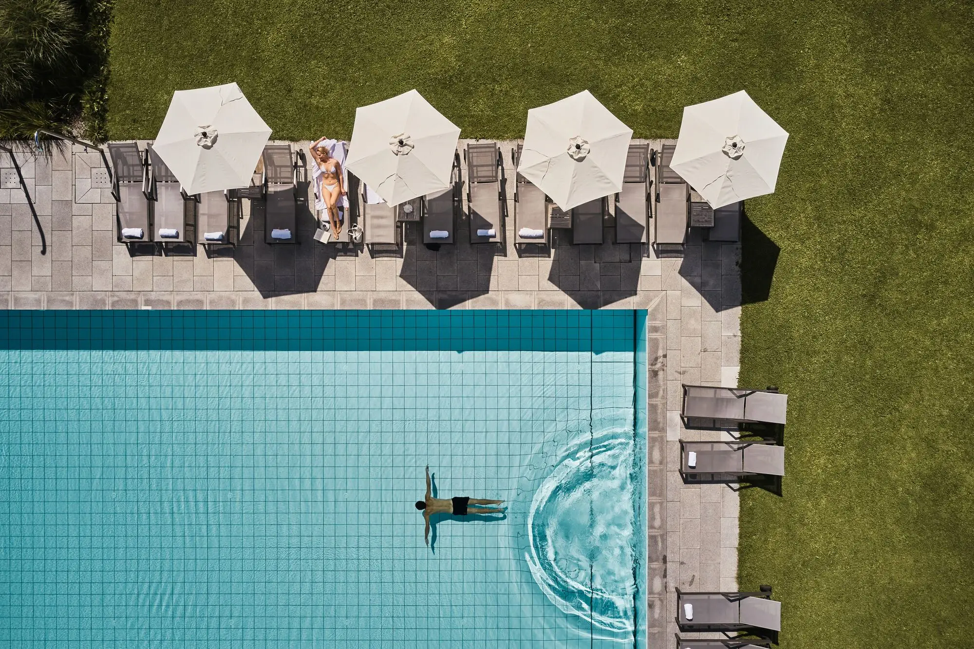 Person swimming in a pool with umbrellas nearby