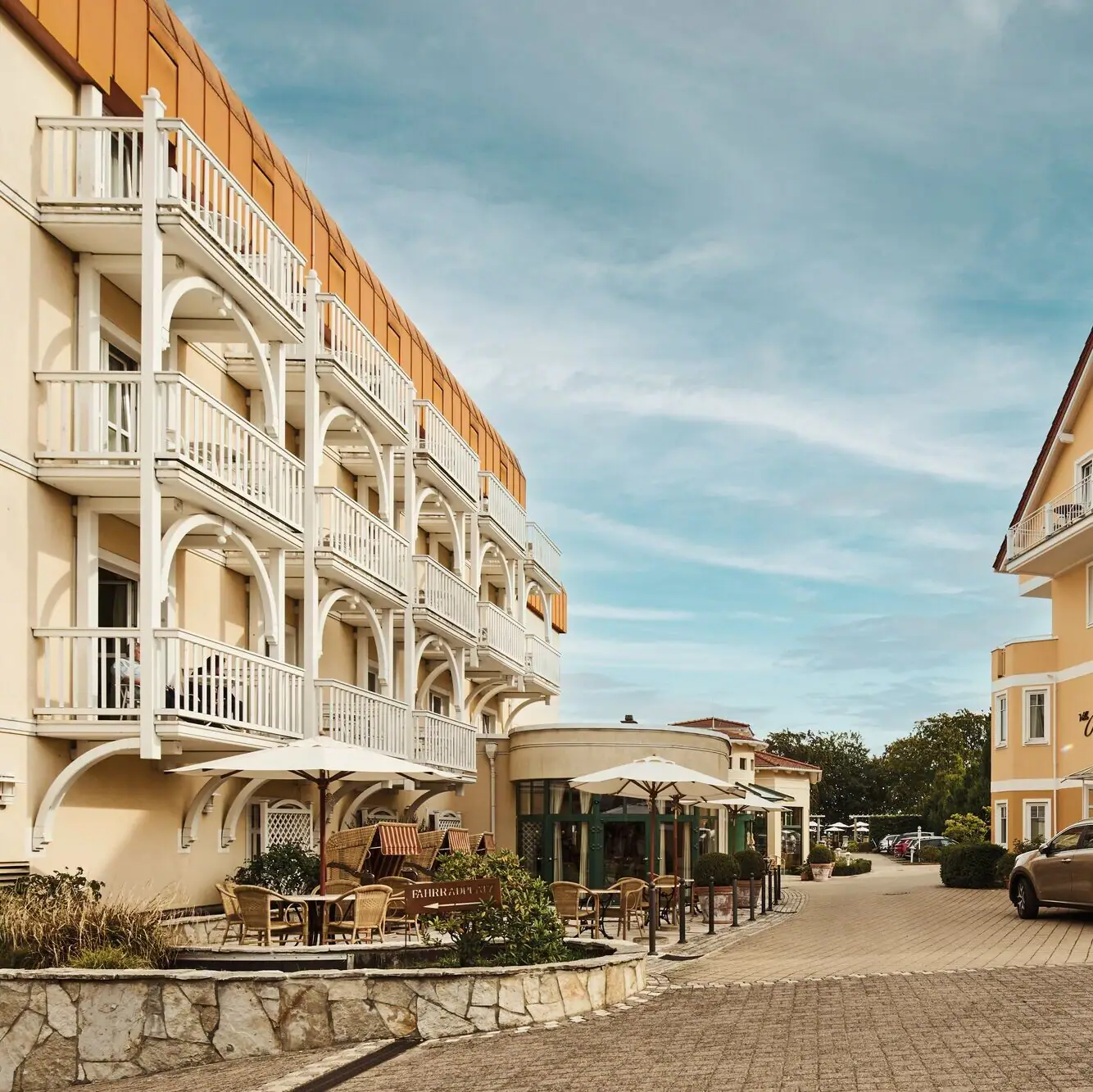 Nordperd & Villas Göhren Street with buildings and cars outside under a cloudy sky.