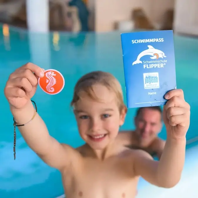 A boy is holding a book and a coin in the pool.