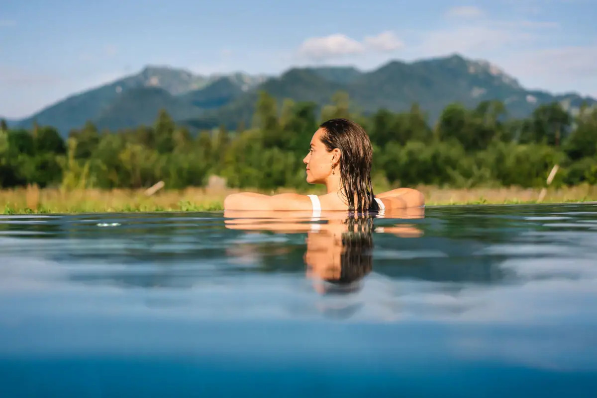 Swimming pool at aja Ruhpolding A woman in a swimming pool with mountains in the background.