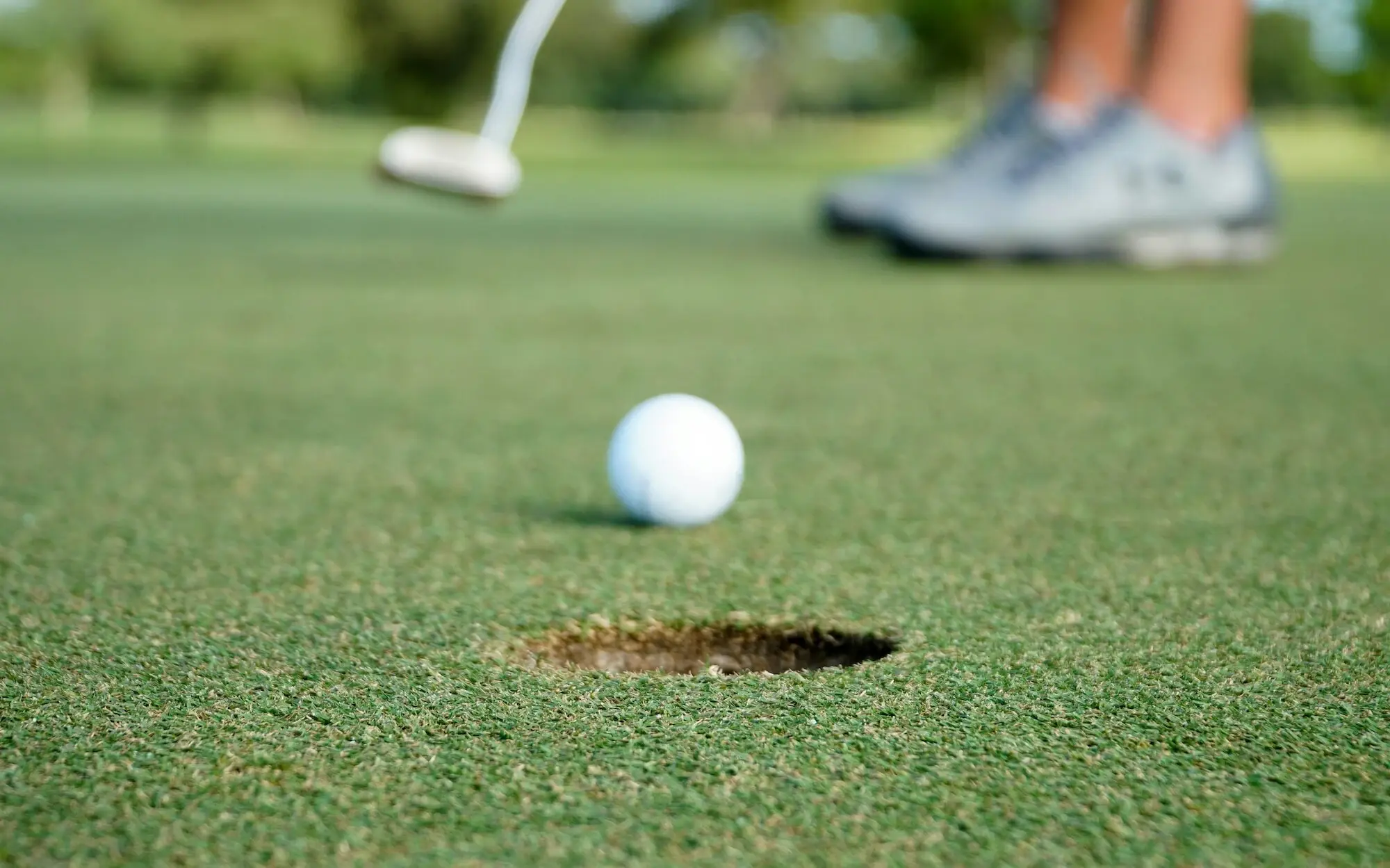 Golf ball near a hole on a golf course.