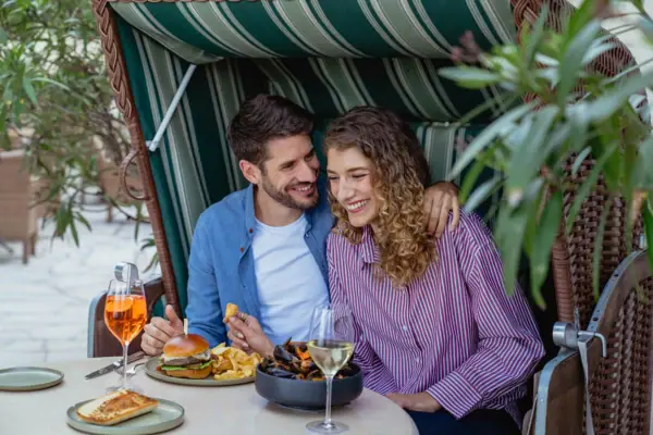 Eating in a beach chair A man and a woman are sitting at a table with food and drinks.