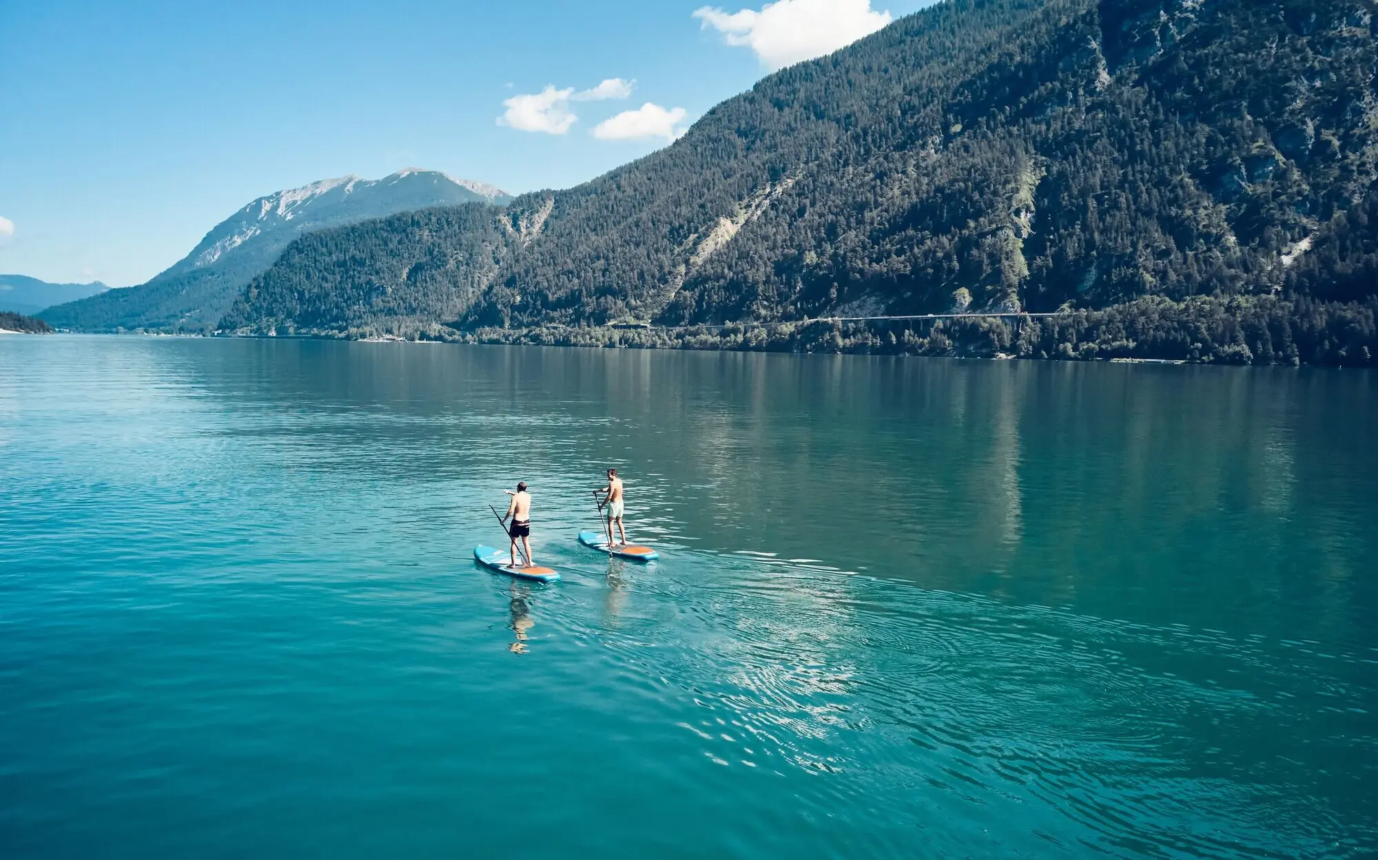 Two people on stand-up paddleboards on a lake.