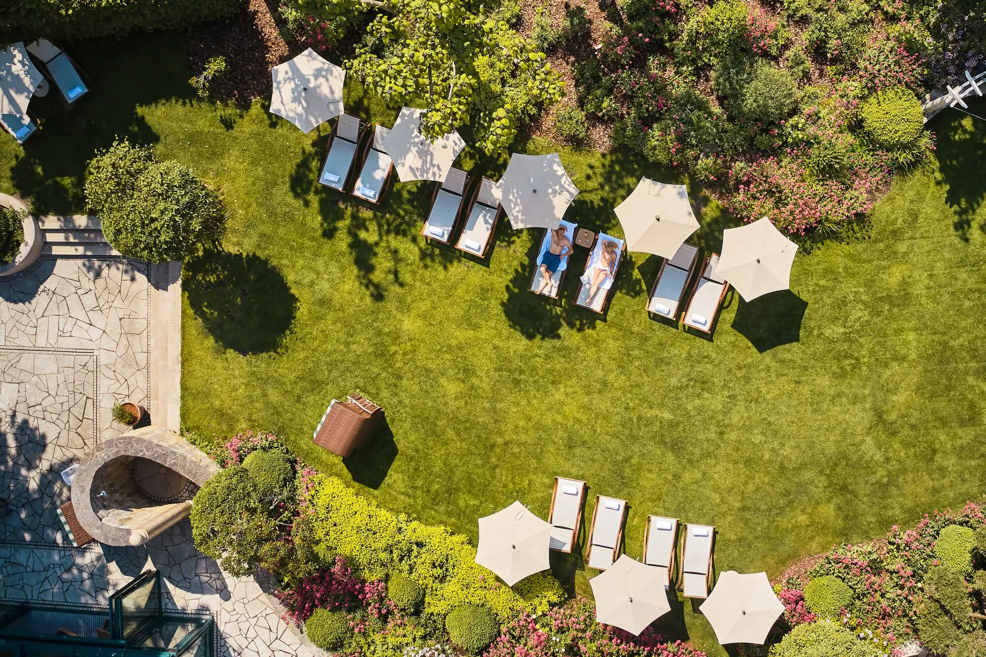 Group of people sitting on deckchairs under parasols in a garden.