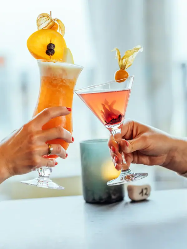 A pair of hands holds glasses with drinks.