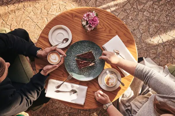 Café Eine Gruppe von Menschen sitzt an einem Tisch mit Kaffee und Kuchen.