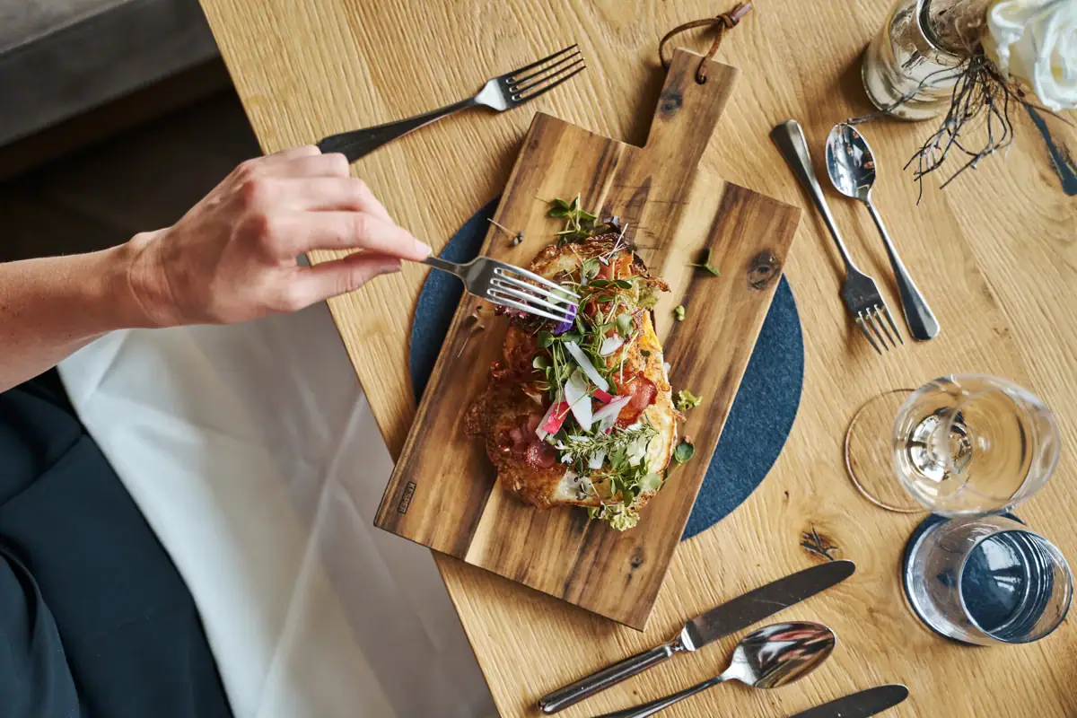 A person eats food on a wooden board.