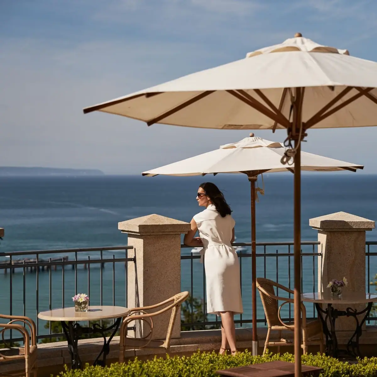 Terrace Nordperd & Villas Woman in a white dress stands on a railing with a large umbrella.