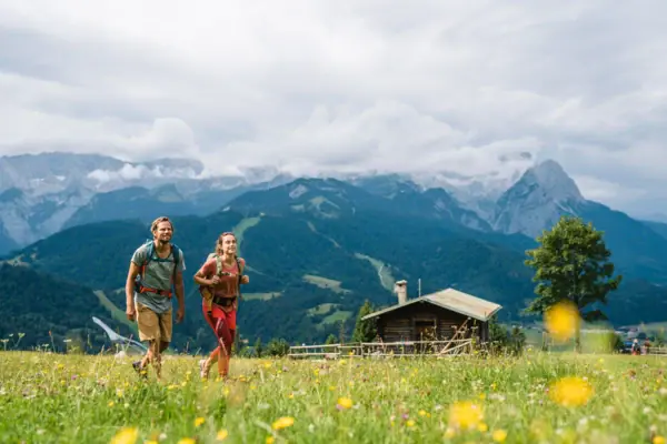 Hiking in Garmisch-Partenkirchen A man and a woman are walking through a field with mountains in the background.