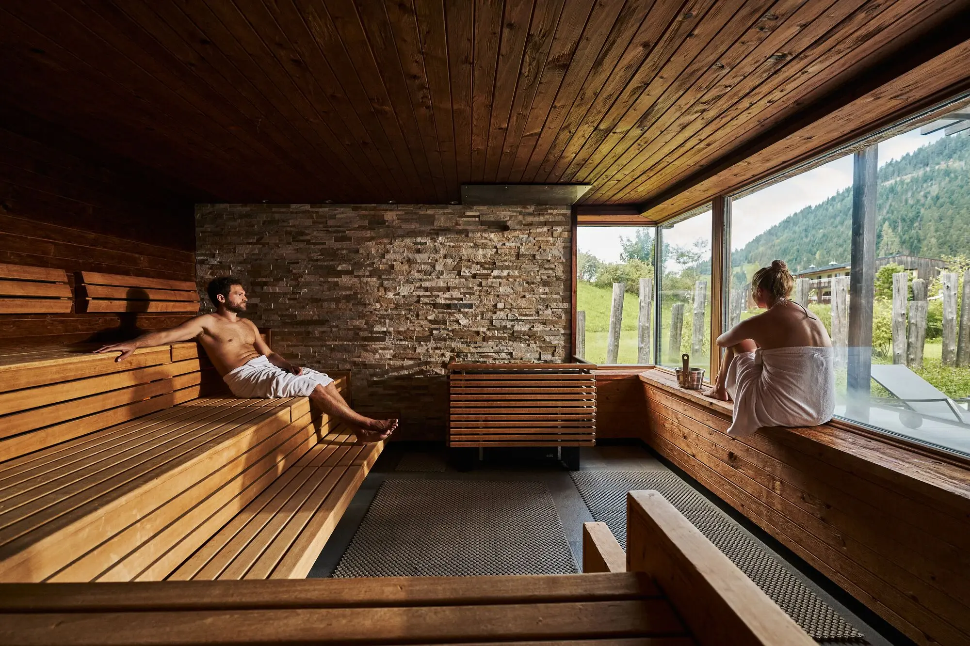 A man and a woman are sitting in a sauna.