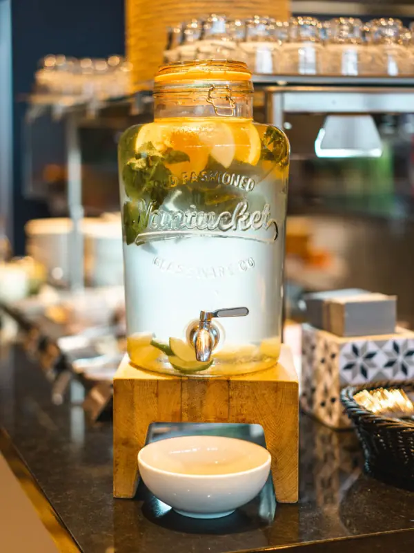 A water dispenser with a drinks dispenser on a table.