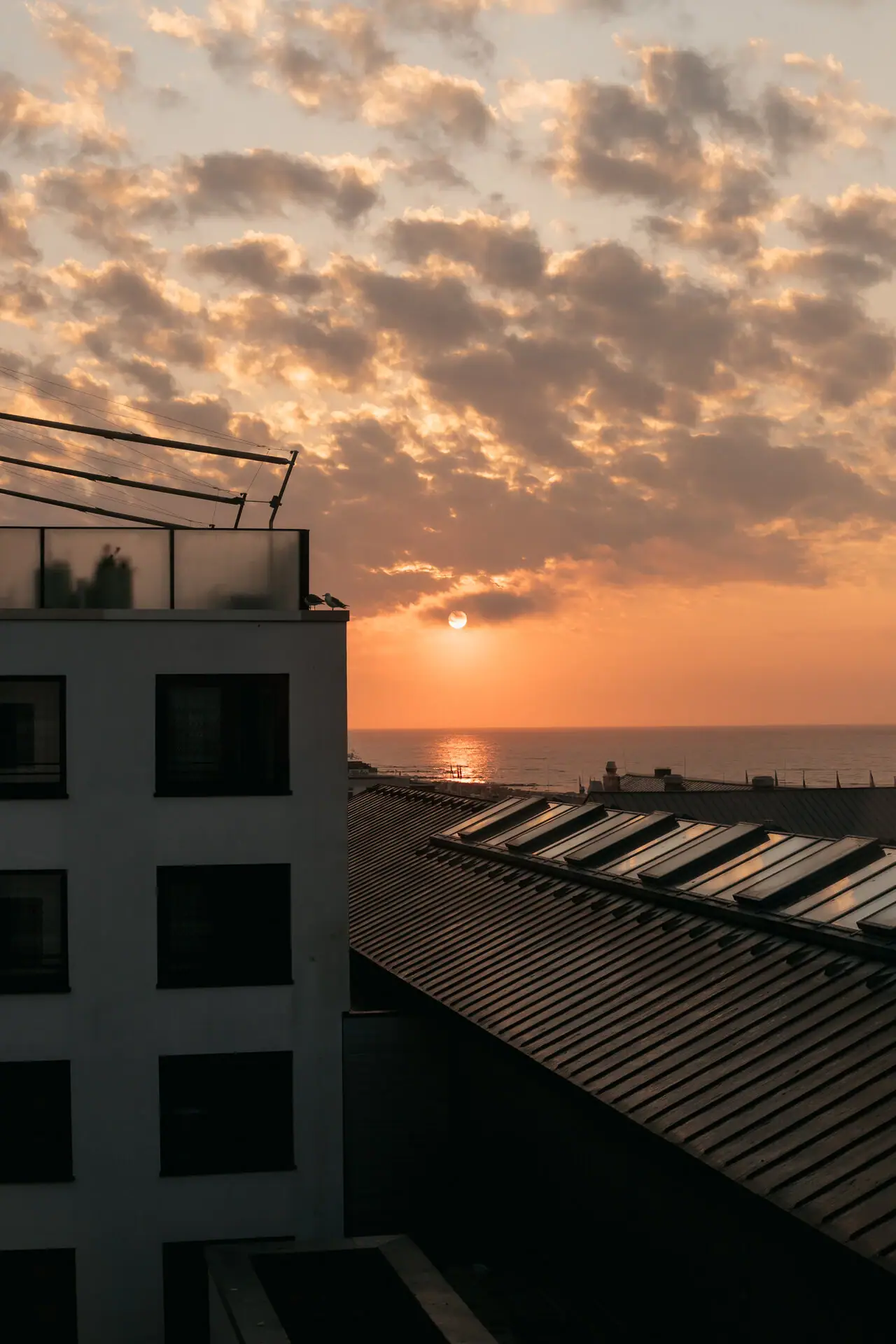 A building with a roof in front of a sunset.