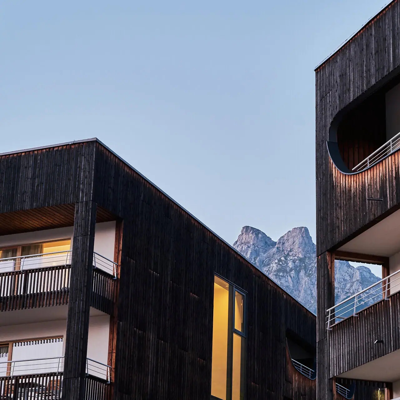A close-up of the hotel building with balconies and the mountains in the background.