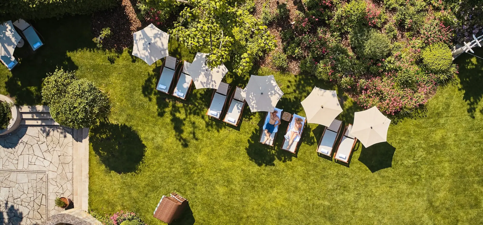 A bird's eye view of a sunbathing lawn with sun loungers and parasols. 