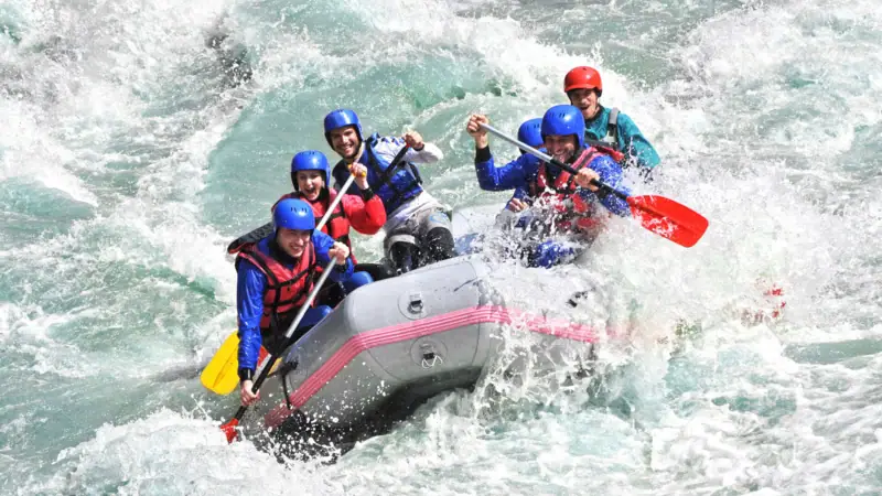 A group of people in a rubber dinghy on the water, all wearing life jackets.