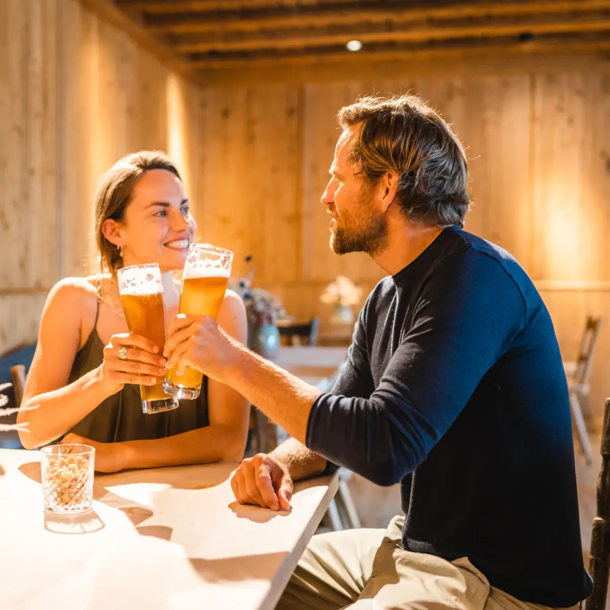 A man and a woman are sitting at a table with beer glasses.