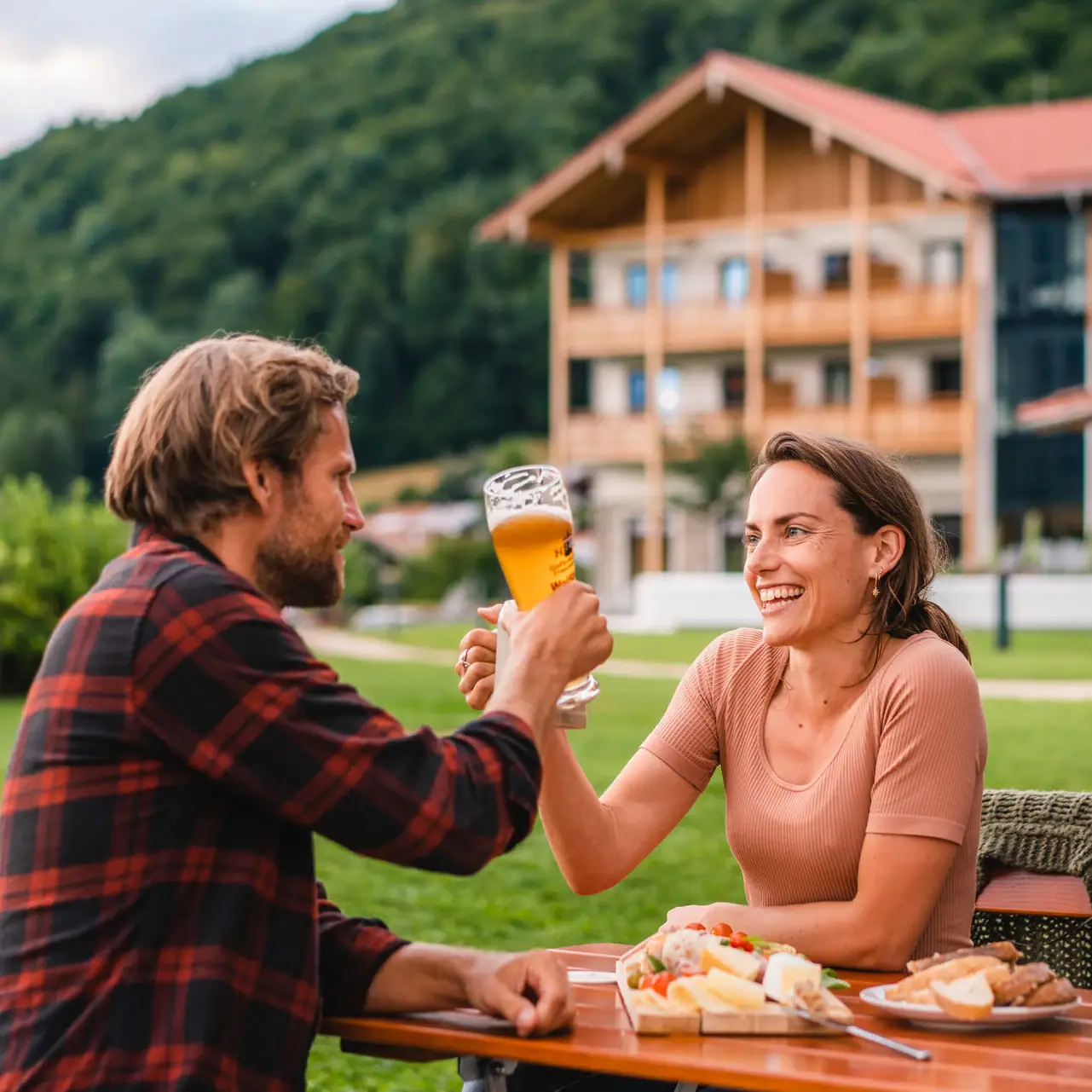 Beer garden aja Ruhpolding A man and a woman are sitting at a table with food and drinks.