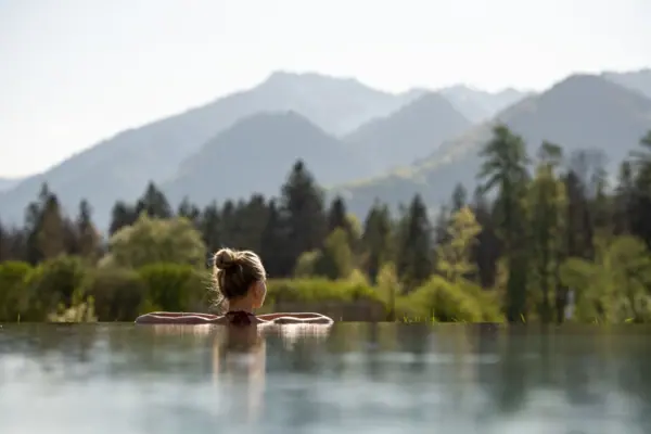A woman in a swimming pool with mountains in the background.