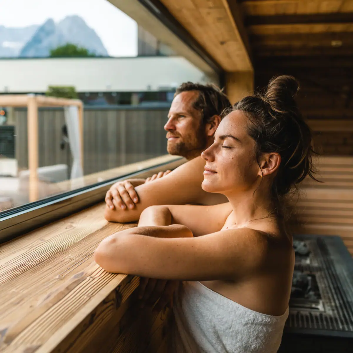 Couple in the sauna A man and a woman in wedding attire leaning against a window.
