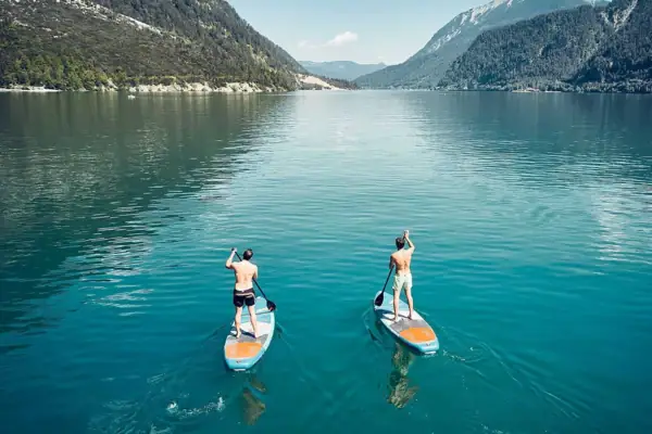 Stand-up paddling Two men on paddleboards on a lake.