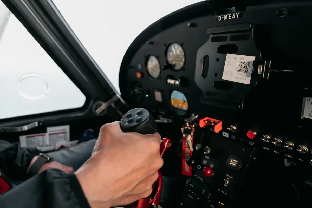 A hand is holding a lever in the cockpit of an aeroplane.