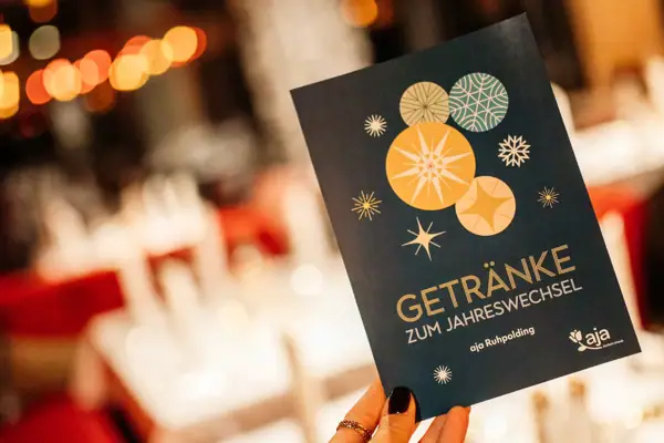 One hand holds a drinks menu for New Year's Eve