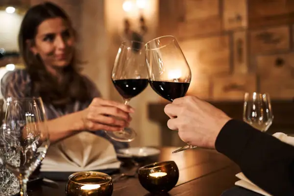 Wine A man and a woman clink glasses of wine at a table.