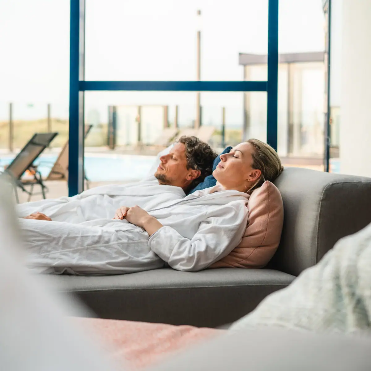 A man and a woman are relaxing on a sofa.
