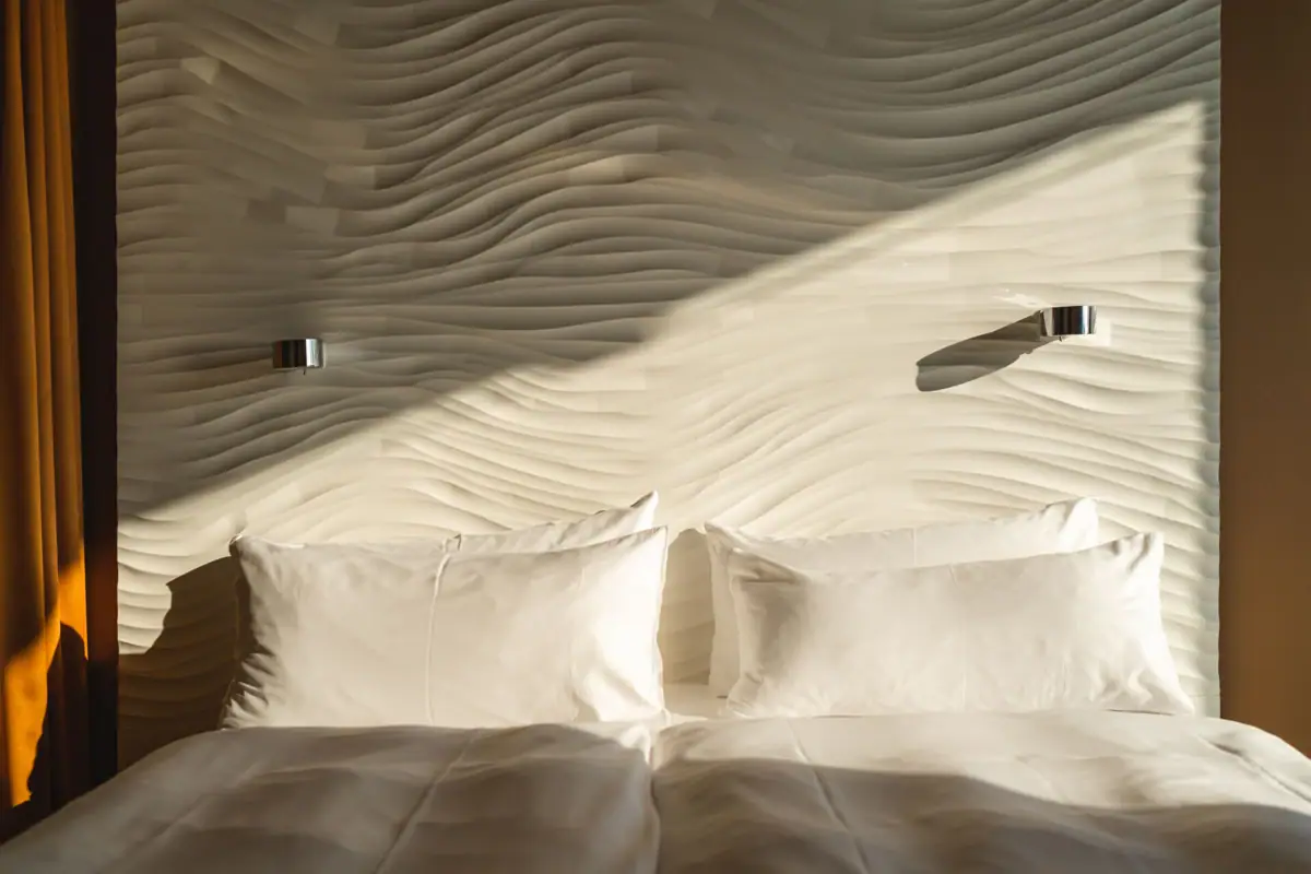 Rooms at the aja Warnemünde A bed with cushions in front of an illuminated wall.