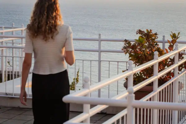 A woman is standing on a deck overlooking the ocean.