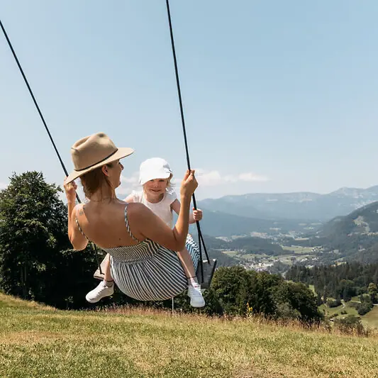 A mother with her child on a swing during a family holiday in Ruhpolding.
