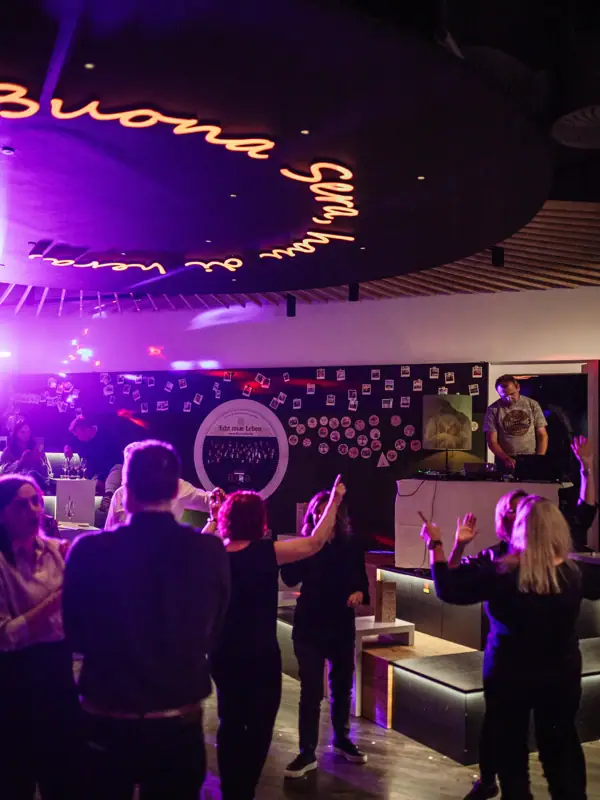 A group of people in a room with a stage and a sign.