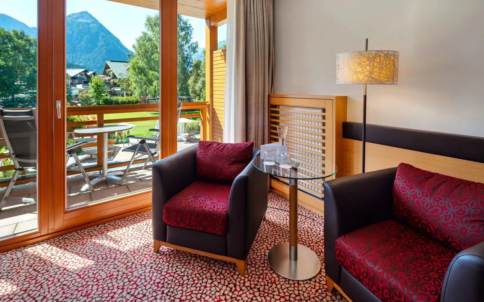 Interior with two armchairs and a table and a mountain landscape can be seen through the window.