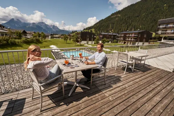 A man and a woman are sitting at a table on a deck.
