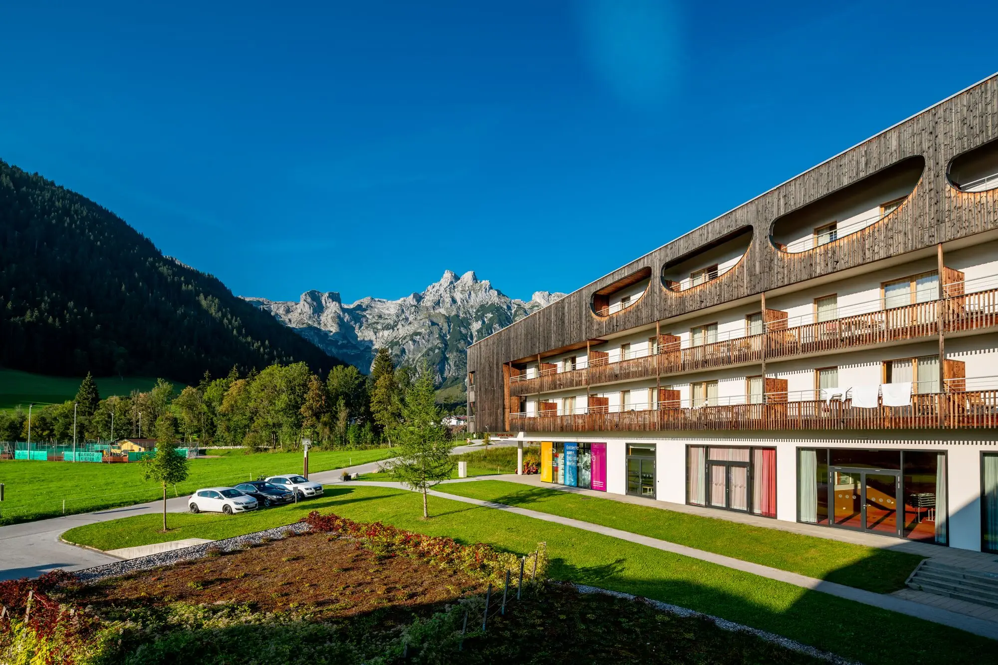 A building with a lawn and cars parked in front.