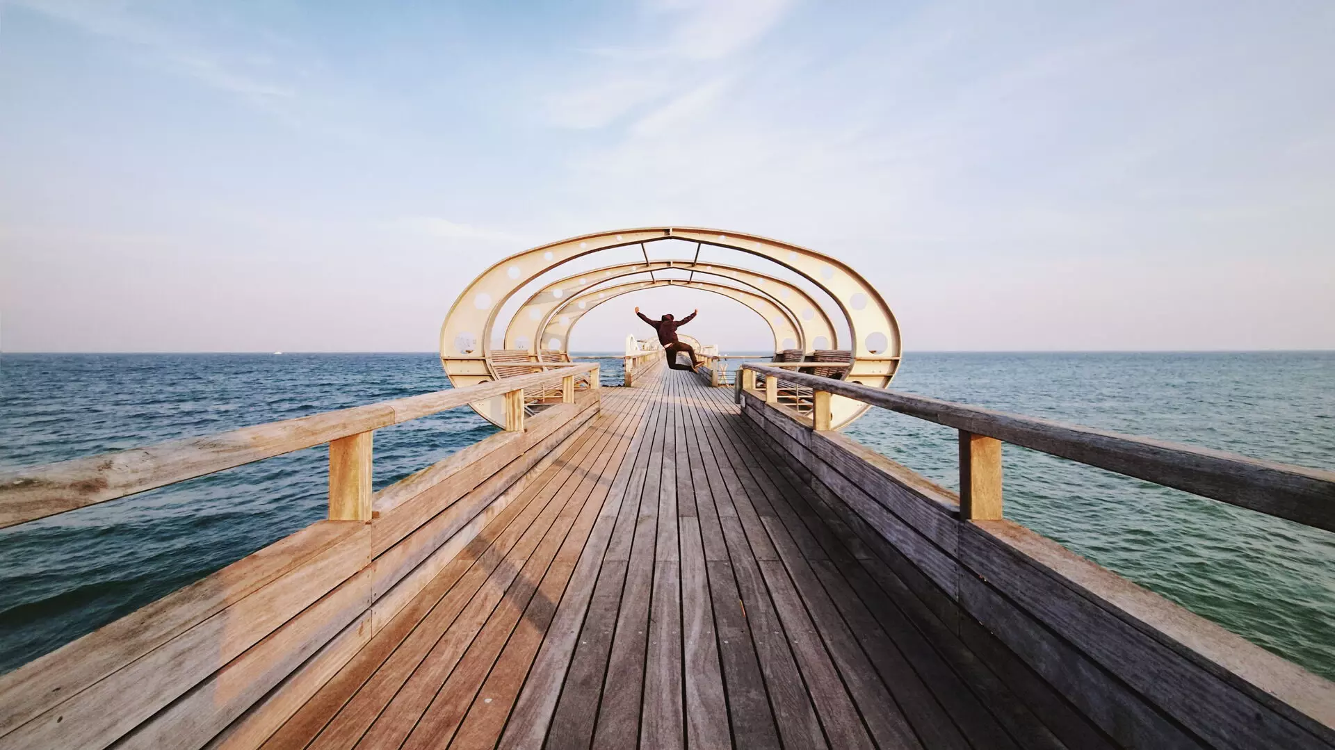 A person on a wooden footbridge jutting out into the water