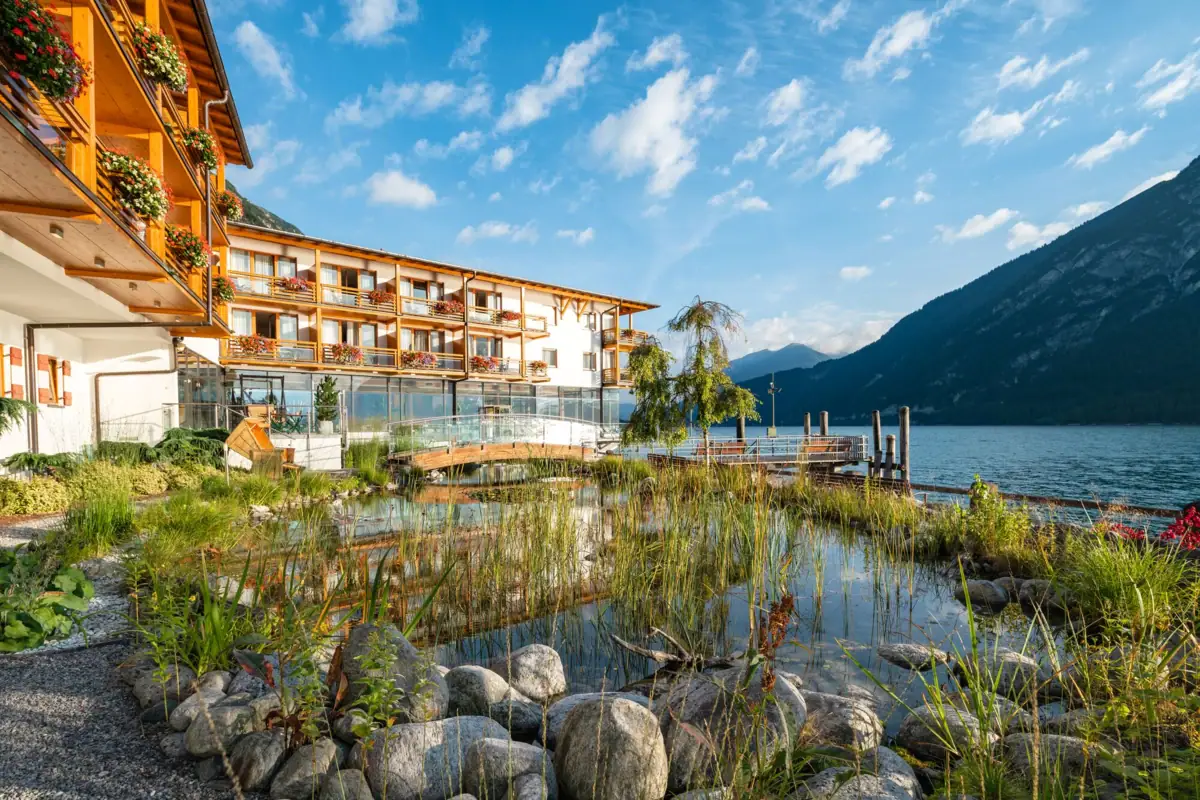Princely house on Lake Achensee A building with a body of water and mountains in the background.
