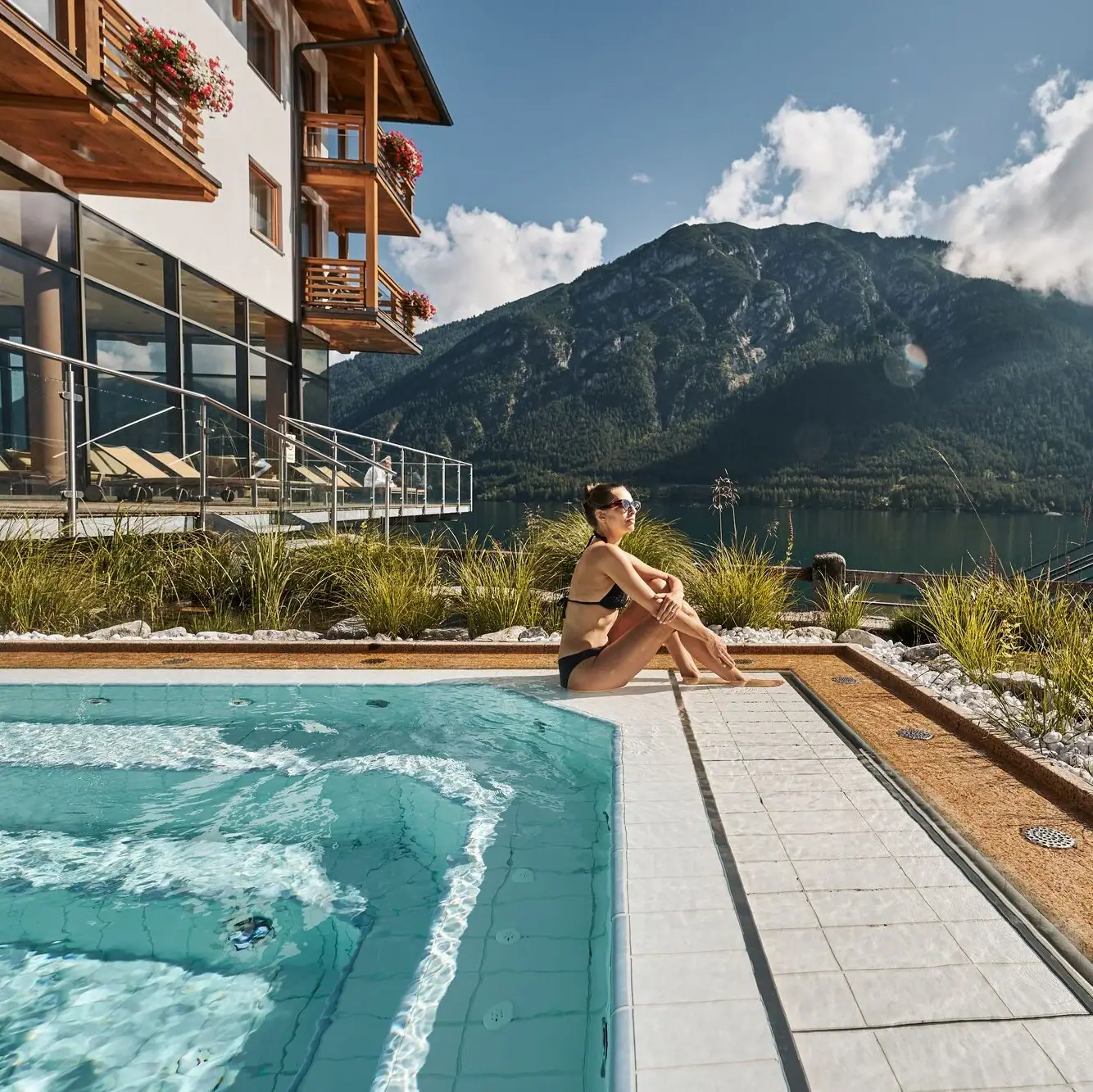Whirlpool A woman sits by a pool with a mountain in the background.