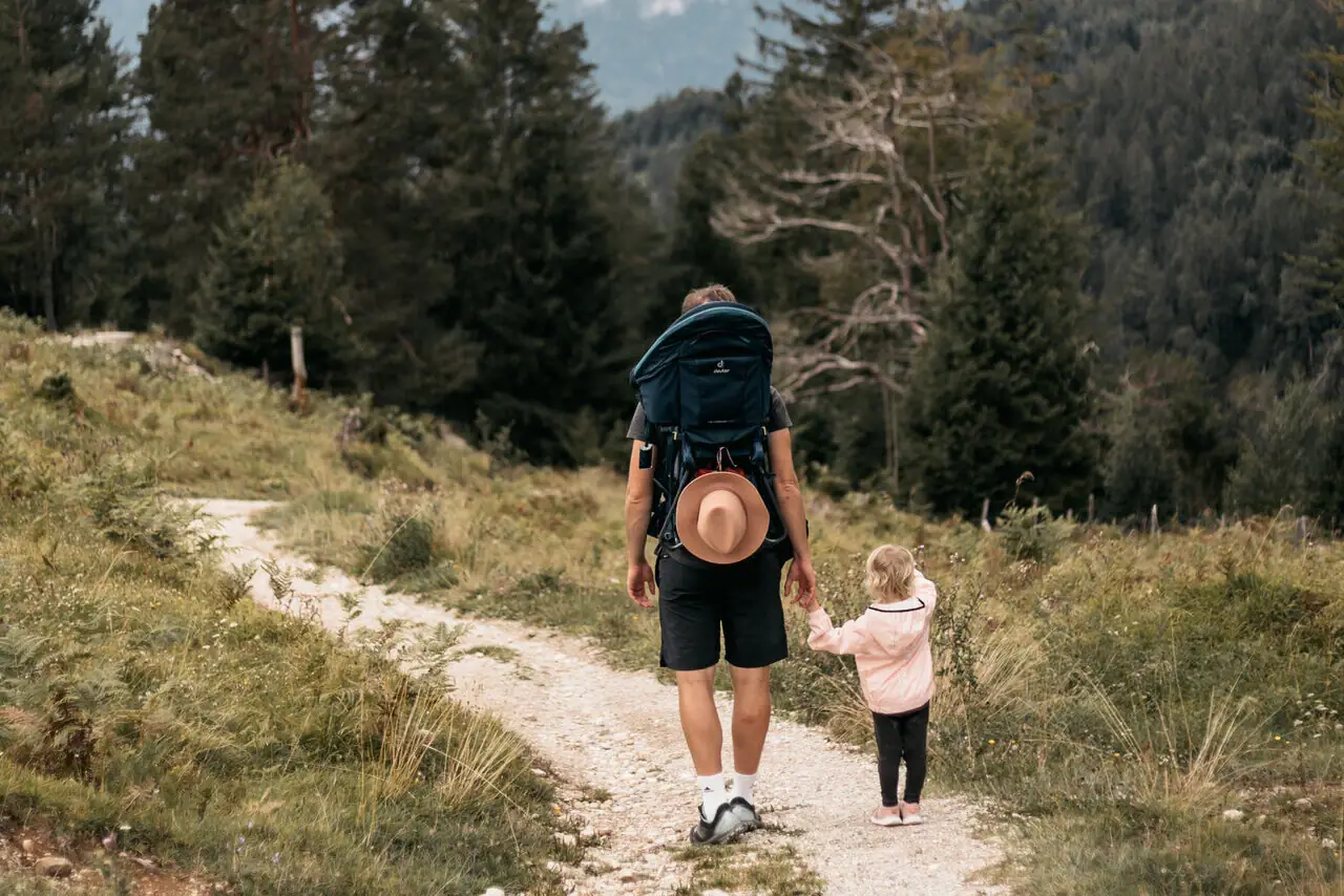 A man and a child are walking along a forest path.