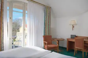 Double room facing the lake with balcony Room with bed, desk and chair.