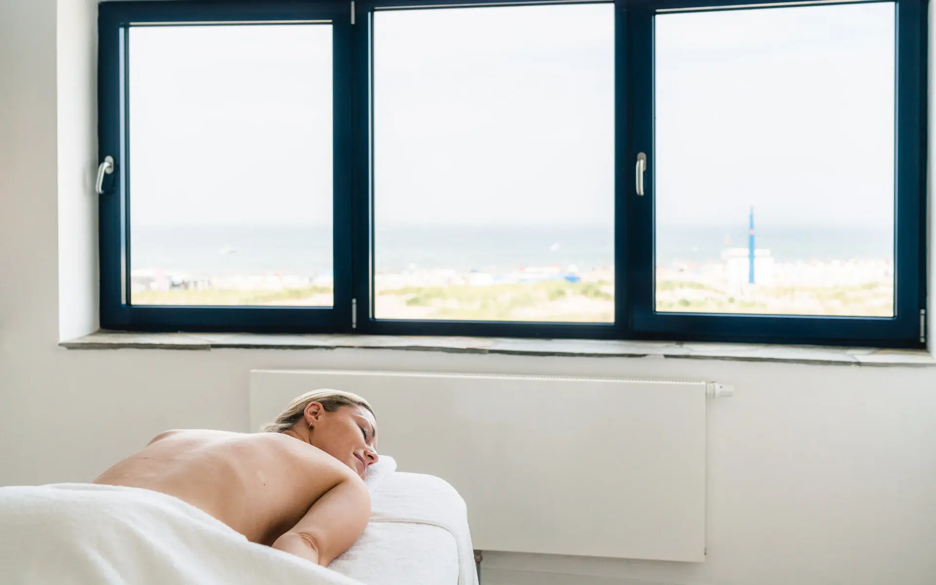 Woman lying on a massage table in a serene indoor setting.