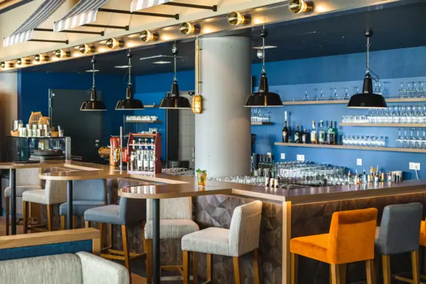 A bar with chairs and glasses.